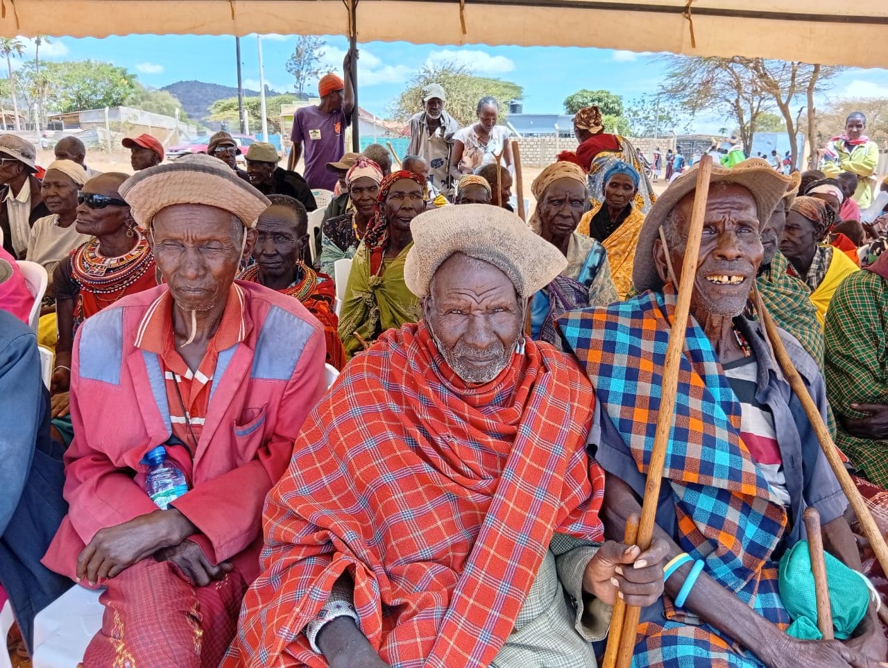 Samburu elders seated together under a shade tent at an NCOA gathering